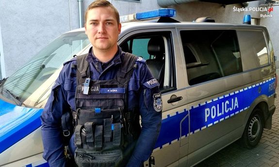 umundurowany policjant Starszy sierżant Paweł Góra przed radiowozem