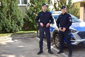 Dwaj policjanci stojący przy radiowozie