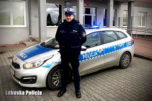 umundurowany policjant ruchu drogowego stoi przy radiowozie