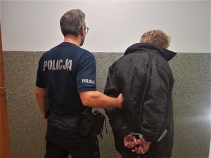 umundurowany policjant prowadzi zatrzymanego mężczyznę