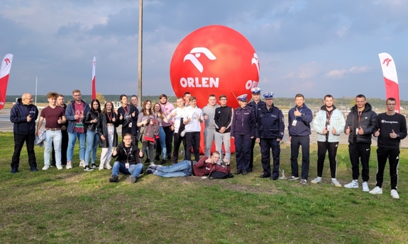 grupa ludzi pozuje do zdjęcia, na środku umundurowani policjanci