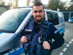 policjant stoi przed radiowozem