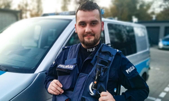 policjant stoi przed radiowozem