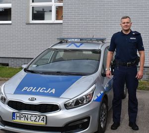 umundurowany policjant stoi przy radiowozie