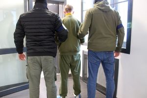 dwaj policjanci prowadzą zatrzymanego mężczyznę