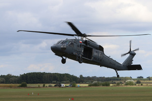 Policyjny śmigłowiec Black Hawk nisko nad trawiastym lądowiedkiem.