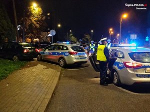 pora nocna - zatrzymane auto i policyjne radiowozy a przed nimi policjanci