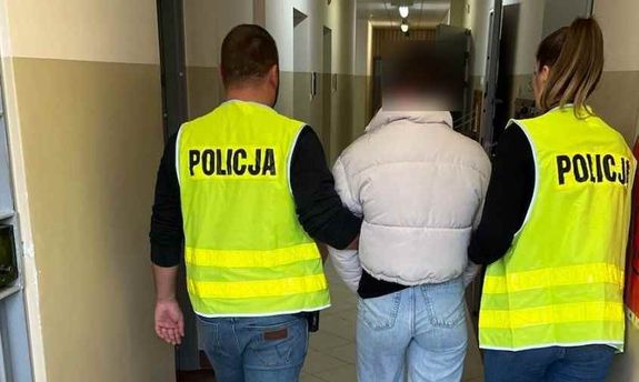 dwaj policjanci w żółtych kamizelkach prowadzą zatrzymaną kobietę