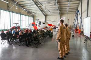 zebrani w hangarze funkcjonariusze straży,  z tyłu widoczny śmigłowiec