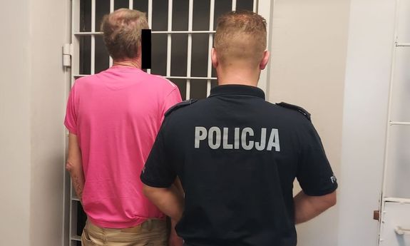 policjant prowadzi zatrzymanego do celi