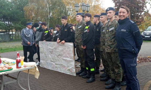 uczniowie klasy mundurowej wraz z policjantami trzymają plakat urodzinowy dla solenizanta