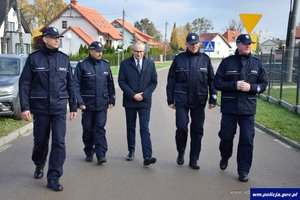 czterech funkcjonariuszy i mężczyzna w garniturze idą drogą