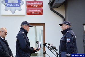 jeden funkcjonariusz wręcza drugiemu klucze od nowego posterunku Policji