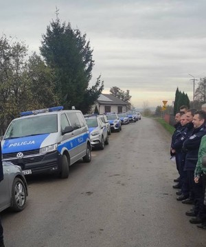 grupa policjantów przy drodze i radiowozy policyjne