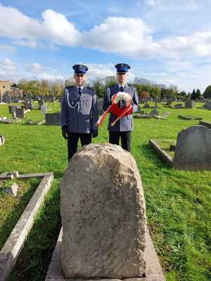 Dwaj policjanci z białoczerwonym wieńcem przed nagrobkiem.