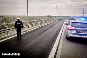 Policjant na wiadukcie, z boku widać zaparkowany policyjny radiowóz