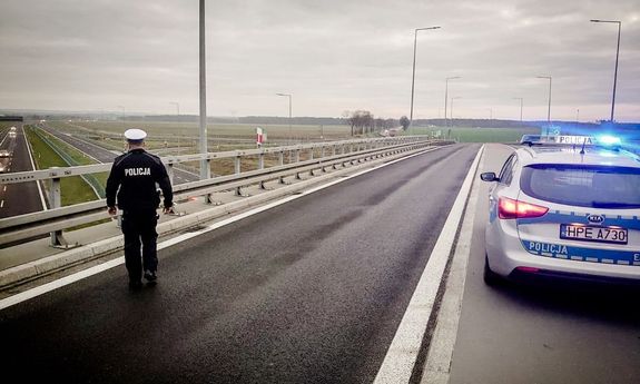 Policjant na wiadukcie, z boku widać zaparkowany policyjny radiowóz