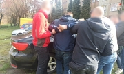 zdjęcie kolorowe: pięciu policjantów i zatrzymany pseudokibic stojący przy samochodzie