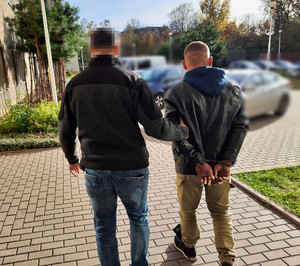 Policjant prowadzi zatrzymanego mężczyznę