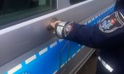 Umundurowany policjant służby prewencyjnej otwiera drzwi radiowozu