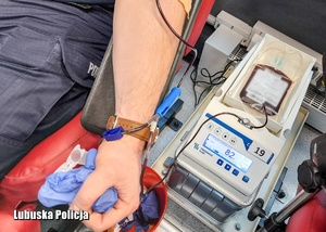 policjant przypięty do aparatury pobierającej krew, w ręku trzyma piłeczkę