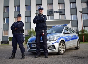 umundurowana policjantka i policjant stoją przed radiowozem