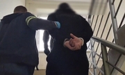 policjant prowadzi zatrzymanego mężczyznę w kajdankach po schodach