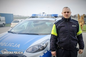 policjant stoi przy radiowozie