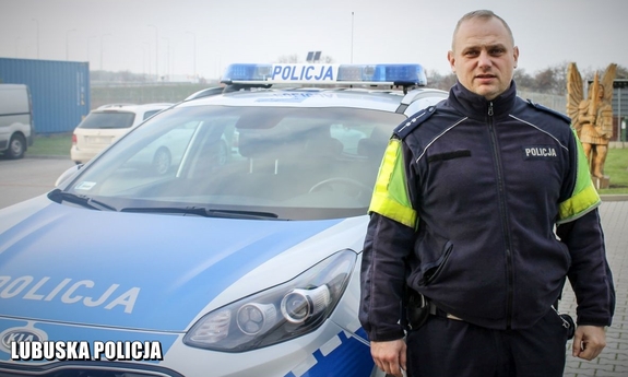 policjant stoi przy radiowozie