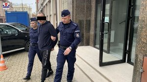 policjant i policjantka prowadzą zatrzymaną osobę