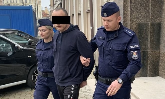 policjant i policjantka prowadzą zatrzymaną osobę