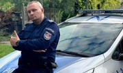 umundurowany policjant stoi przy radiowozie