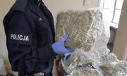 policjant trzyma w rękach worek z narkotykami