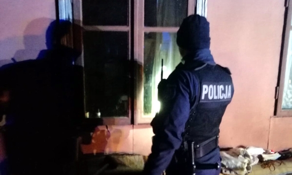 dwaj policjanci zaglądają przez okno do budynku