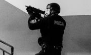 policjant z długa bronią mierzy w kierunku schodów