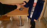 policjant przekazuje dziecku odzyskany telefon komórkowy