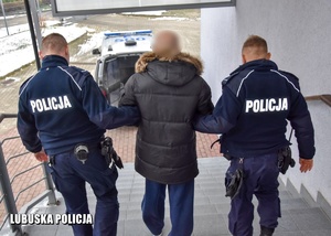 dwaj policjanci prowadzą zatrzymanego schodzą po schodach