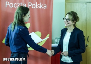 umundurowana policjantka wręcza podziękowania pracownicy poczty