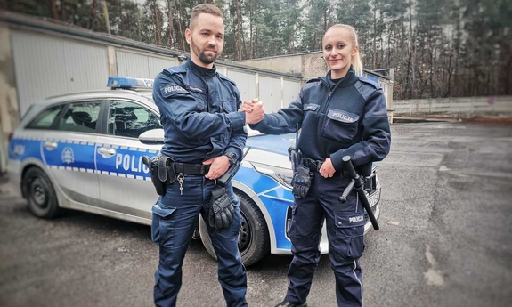 umundurowana policjantka i policjant stoją obok radiowozu