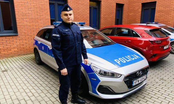 policjant stoi przy radiowozie
