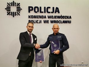 I Zastępca Komendanta Wojewódzkiego Policji we Wrocławiu insp. Robert Frąckowiak i Pan Marcin Starszak – Prezes SOLSTAR HOMES Sp. z o.o. stoją z podpisanymi umowami ściskając sobie dłonie