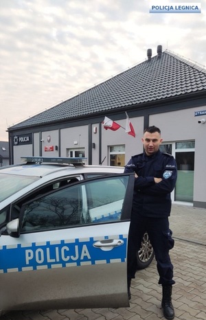 Umundurowany policjant stojący przy radiowozie