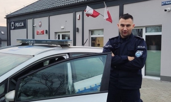 Umundurowany policjant stojący przy radiowozie