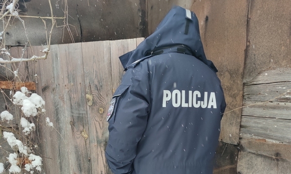 policjant stoi obok budynku