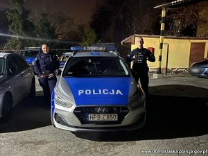 dwoje umundurowanych policjantów przy radiowozie