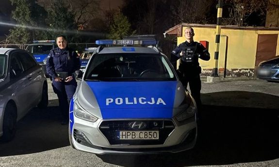 dwoje umundurowanych policjantów przy radiowozie