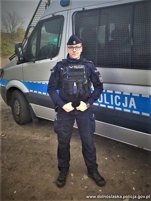 policjant stoi na tle radiowozu policyjnego