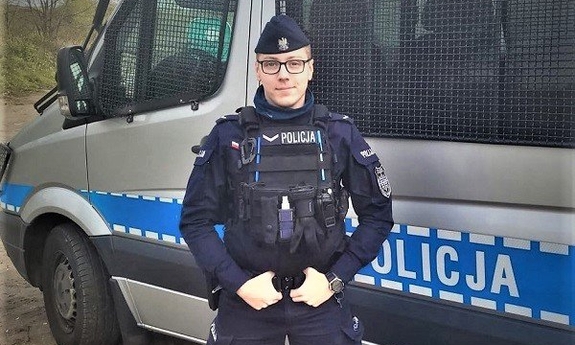 policjant stoi na tle radiowozu policyjnego