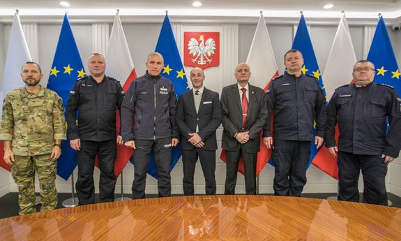 zdjęcie zbiorowe uczestników spotkania, od lewej mężczyzna w moro, dalej dwaj umundurowani oficerowie, dwaj mężczyźni w marynarkach i kolejni dwaj umundurowani oficerowie