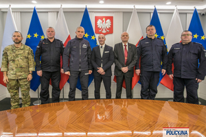 zdjęcie zbiorowe uczestników spotkania, od lewej mężczyzna w moro, dalej dwaj umundurowani oficerowie, dwaj mężczyźni w marynarkach i kolejni dwaj umundurowani oficerowie